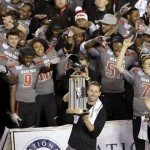 Texas Tech head coach Kliff Kingsbury, bottom center, raises the trophy in front of his team after Texas Tech beat Arizona State in the Holiday Bowl NCAA college football game Monday, Dec. 30, 2013, in San Diego. (AP Photo/Gregory Bull)