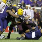 Arizona State's D.J. Foster is brought down by a trio of Washington defenders in the first half of an NCAA college football game Saturday, Oct. 25, 2014, in Seattle. (AP Photo/Elaine Thompson)