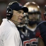 Arizona's head coach Rich Rodriguez, left, looks at the game clock during a timeout against Northern Arizona during the second half of an NCAA college football game at Arizona Stadium in Tucson, Ariz., Friday, Aug. 30, 2013. (AP Photo/John Miller)
