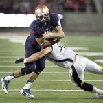Arizona's starting quarterback B.J. Denker, left, is tackled by Northern Arizona's Quentin Kantaris (96) during the first half of an NCAA college football game at Arizona Stadium in Tucson, Ariz., Friday, Aug. 30, 2013. (AP Photo/Wily Low)
