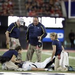 Northern Arizona head coach Jerome Souers, standing center, watches the trainers evaluate his player Jacob Julian, on the ground, during the first half of an NCAA college football game against Arizona at Arizona Stadium in Tucson, Ariz., Friday, Aug. 30, 2013. (AP Photo/Wily Low)
