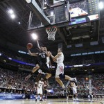 Harvard's Christian Webster, left puts a shot up past Arizona defenders, including Kaleb Tarczewski, right, in the first half during a third-round game in the NCAA men's college basketball tournament in Salt Lake City on Saturday, March 23, 2013. (AP Photo/George Frey)
