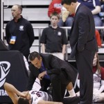 An Arizona trainer and coach Sean Miller, right, look over injured player Grant Jarrett during the first half against Harvard in a third-round game in the NCAA men's college basketball tournament in Salt Lake City on Saturday, March 23, 2013. (AP Photo/George Frey)
