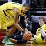 Arizona's Nick Johnson, left, turns the ball over to Oregon's Tony Woods after falling to the court with E.J. Singler, right, during the first half of their NCAA college basketball game, Thursday, Jan. 10, 2013, in Eugene, Ore. (AP Photo/Chris Pietsch)