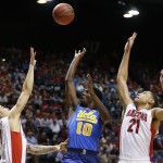 UCLA's Isaac Hamilton, center, shoots between Arizona's Gabe York, left, and Brandon Ashley during the first half of an NCAA college basketball game in the semifinals of the Pac-12 conference tournament Friday, March 13, 2015, in Las Vegas. (AP Photo/John Locher)