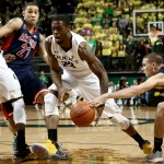 Oregon forward Elgin Cook, center, drives to the basket against Arizona's Brandon Ashley, left, and another defender during the second half of an NCAA college basketball game Thursday, Jan. 8, 2015, in Eugene, Ore. (AP Photo/Ryan Kang)