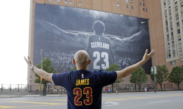 A fan poses for a photo in front of a billboard featuring Cleveland Cavaliers forward LeBron James ...