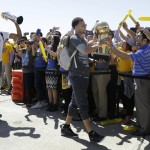 
              Golden State Warriors guard Stephen Curry, center, walks past cheering team employees as he carries the Larry O'Brien championship trophy in front of forward Andre Iguodala, lifting the NBA Finals MVP trophy, after the team landed in Oakland, Calif., Wednesday, June 17, 2015. The Warriors beat the Cleveland Cavaliers to win their first NBA championship since 1975. (AP Photo/Jeff Chiu)
            