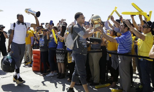 Golden State Warriors guard Stephen Curry, center, walks past cheering team employees as he carries...