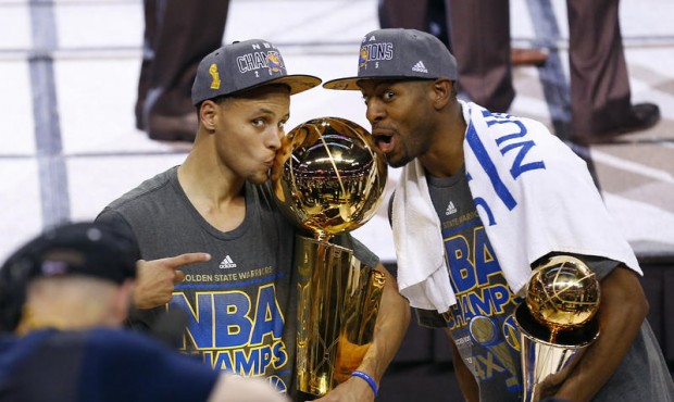 Golden State Warriors guard Stephen Curry, left, holds the championship trophy and Andre Iguodala h...
