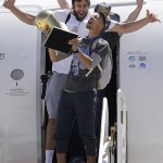 
              Golden State Warriors guard Stephen Curry, foreground, yells as he carries the Larry O'Brien NBA championship trophy in front of center Andrew Bogut after the team's flight landed in Oakland, Calif., Wednesday, June 17, 2015. The Warriors defeated the Cleveland Cavaliers to win their first NBA championship since 1975. (AP Photo/Jeff Chiu)
            