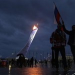 A fan carries a Russian flag while walking in the Olympic Plaza during the 2014 Winter Olympics, Tuesday, Feb. 18, 2014, in Sochi, Russia. (AP Photo/Darron Cummings)