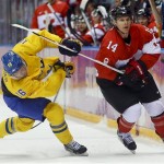 Canada forward Chris Kunitz, right, passes off the puck against Sweden forward Marcus Kruger during the first period of the men's gold medal ice hockey game at the 2014 Winter Olympics, Sunday, Feb. 23, 2014, in Sochi, Russia. (AP Photo/Matt Slocum)