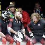 The team from Canada CAN-3, with Justin Kripps, Jesse Lumsden, Cody Sorensen and Ben Coakwell, sit on the finish area after crashing near the finish of turn sixteen during the men's four-man bobsled competition at the 2014 Winter Olympics, Saturday, Feb. 22, 2014, in Krasnaya Polyana, Russia. (AP Photo/Michael Sohn)