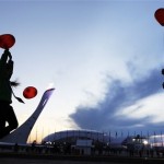 The Olympic flame burns in the background at the Olympic Park as children play with heart shaped balloons in celebration of Valentine's Day at the 2014 Winter Olympics, Friday, Feb. 14, 2014, in Sochi, Russia. (AP Photo/David Goldman)