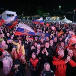 Supporters wave the Russian national flag and scream "Russia" as the Russian team make their appearance during the live telecast of the 2014 Winter Olympics opening ceremony, Friday, Feb. 7, 2014, in downtown Sochi, Russia. (AP Photo/Wong Maye-E)