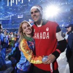 A Canadian athlete, right, poses for a photograph with a volunteer during the closing ceremony of the 2014 Winter Olympics, Sunday, Feb. 23, 2014, in Sochi, Russia. (AP Photo/Darron Cummings)