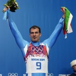 Armin Zoeggeler of Italy holds up the Italian flag and flowers during the flower ceremony after he won the bronze medal during the men's singles luge final at the 2014 Winter Olympics, Sunday, Feb. 9, 2014, in Krasnaya Polyana, Russia. (AP Photo/Michael Sohn)