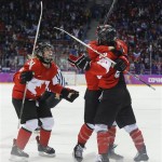 Haley Irwin of Canada (21) celebrates with teammates Marie-Philip Poulin (29) and Meghan Agosta-Marciano (2) after Poulin scored the tying goal against the USA during the third period of the women's gold medal ice hockey game at the 2014 Winter Olympics, Thursday, Feb. 20, 2014, in Sochi, Russia. (AP Photo/Matt Slocum)