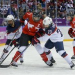 Caroline Ouellette of Canada (13) battles Kelli Stack (16) and Michelle Picard of the United States (23) for the puck during the first period of the women's gold medal ice hockey game at the 2014 Winter Olympics, Thursday, Feb. 20, 2014, in Sochi, Russia. (AP Photo/Matt Slocum)