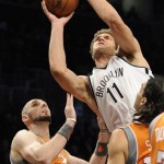 Brooklyn Nets' Brook Lopez (11) shoots between Phoenix Suns' Marcin Gortat (4) and Luis Scola (14) in the first half of an NBA basketball game on Friday, Jan., 11, 2013 at Barclays Center in New York. The Nets won 99-79. (AP Photo/Kathy Kmonicek)