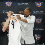 Phoenix Suns' Tyson Chandler, second from right, drapes his new uniform over Suns senior adviser Lon Babby, second from left, as head coach Jeff Hornacek, right, and general manager Ryan McDonough both look on, after the newly signed free agent was introduced to the media during a news conference Thursday, July 9, 2015, in Phoenix. (AP Photo/Ross D. Franklin)