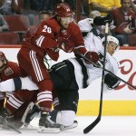 Arizona Coyotes' Chris Summers (20) and Brandon McMillan (22) sends Los Angeles Kings' Jordan Nolan, right, to the ice on a hard hit during the first period of an NHL hockey game Saturday, Oct. 11, 2014, in Glendale, Ariz. (AP Photo/Ross D. Franklin)