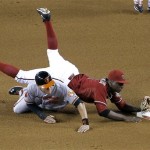 Arizona Diamondbacks' Didi Gregorius is knocked down after forcing out Baltimore Orioles' Manny Machado, bottom, on a ball hit by Adam Jones, who was safe at first during the first inning of a baseball game, Wednesday, Aug. 14, 2013, in Phoenix. (AP Photo/Matt York)