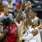 Miami forward Kenny Kadji, right, takes a shot over Arizona's Angelo Chol, left, and Mark Lyons, bottom center, in the second half of an NCAA college basketball game in the Diamond Head Classic Sunday, Dec. 23, 2012, in Honolulu. Arizona defeated Miami 69-50. (AP Photo/Eugene Tanner)