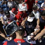 Washington Nationals outfielder Bryce Harper, bottom, signs autographs for fans before an exhibition spring training baseball game against the Miami Marlins Wednesday, Feb. 27, 2013, in Viera, Fla. (AP Photo/David J. Phillip)