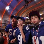 New York Giants fans, from left, Jeff Becker and his son Reed, 11, both of Livingston, N.J., and Nate Casharay, 10, of Cornwall, N.Y., wait for the announcement of the Giants' third round pick, the 81st overall, during the NFL football draft, Friday, April 26, 2013, at Radio City Music Hall in New York. (AP Photo/Jason DeCrow)