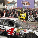 Kevin Harvick, standing to the right of the winner's trophy, joins his crew in posing for photographers in Victory Lane after winning the NASCAR Sprint Cup Series auto race Sunday, March 2, 2014, in Avondale, Ariz. (AP Photo/Ross D. Franklin)