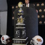 Oklahoma State coach Mike Gundy answers reporters' questions behind the Fiesta Bowl Championship trophy during a news conference, Monday, Dec. 26, 2011, after the team's arrival at Sky Harbor International Airport in Phoenix. Oklahoma State is scheduled to play Stanford in the Fiesta Bowl NCAA college football game Monday, Jan. 2. (AP Photo/Paul Connors)