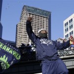 Seattle Seahawks running back Marshawn Lynch throws pieces of candy while riding on the hood of a vehicle during the Super Bowl champions parade on Wednesday, Feb. 5, 2014, in Seattle. The Seahawks defeated the Denver Broncos 43-8 in NFL football's Super Bowl XLVIII on Sunday. (AP Photo/Elaine Thompson)
