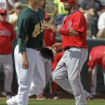 Los Angeles Angels' Albert Pujols reacts as he scores in front of Oakland Athletics' Brad Peacock during the first inning of a spring training baseball game Monday, March 5, 2012, in Phoenix. (AP Photo/Darron Cummings)