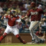 Arizona Diamondbacks' Willie Bloomquist, right, scores after teammate Jason Kubel reached base on a fielding error by St. Louis Cardinals left fielder Matt Holliday as Cardinals catcher Tony Cruz, left, tries to throw Kubel out at third during the sixth inning of a baseball game on Wednesday, June 5, 2013, in St. Louis. (AP Photo/Jeff Roberson)