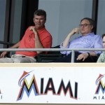 Miami Marlins owner Jeffrey Loria, center, watches the ninth inning of an exhibition spring training baseball game against the New York Mets, Tuesday, Feb. 26, 2013, in Jupiter, Fla. The Marlins won 7-5. (AP Photo/Julio Cortez)