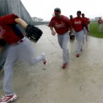 St. Louis Cardinals pitchers run off a practice field as heavy rain begins to fall during spring training baseball, Thursday, Feb. 14, 2013, in Jupiter, Fla. The players spent most of the day inside the clubhouse because of the weather. (AP Photo/Julio Cortez)
