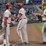 Arizona Diamondbacks' Ryan Roberts, left, congratulates Justin Upton, center, and Miguel Montero, right, after they scored on a Geoff Blum two-RBI single against the Colorado Rockies during the first inning of a baseball game on Friday, April 13, 2012, in Denver. (AP Photo/Jack Dempsey)