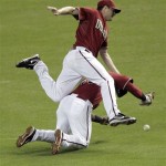 Arizona Diamondbacks pitcher Daniel Hudson, top, collides with teammate Juan Miranda while trying to catch a foul ball hit by Florida Marlins' Mike Standon during the third inning of a baseball game, Wednesday, June 1, 2011, in Phoenix. (AP Photo/Matt York)