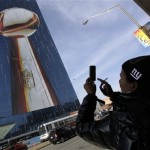 Michele Turner, of Teaneck, N.J., takes a picture of a building displaying the likeness of the Vince Lombardi Trophy in Indianapolis, Friday Feb. 3, 2012. The New England Patriots are scheduled to face the New York Giants in Super Bowl XLVI in Indianapolis on Feb 5. (AP Photo/Elise Amendola)