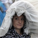 Jennifer Parod, Tucson, Az., looks out from her plastic covered hat before the 139th Kentucky Derby at Churchill Downs Saturday, May 4, 2013, in Louisville, Ky. (AP Photo/Garry Jones)
