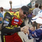 Driver Clint Bowyer signs an autograph for some young fans before the start of the AdvoCare 500 NASCAR Sprint Cup Series auto race at Phoenix International Raceway, Sunday, Nov. 10, 2013 in Avondale, Ariz. (AP Photo/Ralph Freso)