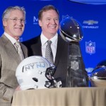 Roger Goodell, commissioner of the National Football League, center, and Pete Carroll, head coach of the Seattle Seahawks, pose for a photograph beside the Vince Lombardi and MVP trophy during a news conference at the Super Bowl XLVIII Media Center at the Sheraton hotel, Monday, Feb. 3, 2014, in New York. The Seattle Seahawks defeated the Denver Broncos, 43-8. (AP Photo/John Minchillo)
