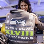 Julie Keim, of Mulkiteo, Wash., smiles as she unfolds a Seattle Seahawks' Super Bowl championship shirt to check on sizing at the team store, Monday, Feb. 3, 2014, in Seattle. The Seahawks defeated the Denver Broncos on Sunday in the Super Bowl XLVIII NFL football game, 43-8. (AP Photo/Elaine Thompson)