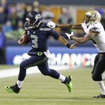 Seattle Seahawks quarterback Russell Wilson, left, pushes off New Orleans Saints cornerback Keenan Lewis, right, as Wilson keeps the ball in the first half of an NFL football game, Monday, Dec. 2, 2013, in Seattle. (AP Photo/Elaine Thompson)