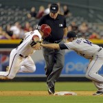 Arizona Diamondbacks' Gerardo Parra, left, tries to avoid the tag of Colorado Rockies' Josh Rutledge while advancing on a fly out during the eighth inning of a baseball game, Thursday, April 25, 2013, in Phoenix. Umpire Lance Barksdale, rear, called Parra safe. (AP Photo/Matt York)