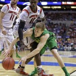 Oregon forward E.J. Singler passes the ball around Louisville center Gorgui Dieng (10) during the second half of a regional semifinal in the NCAA college basketball tournament, Friday, March 29, 2013, in Indianapolis. Louisville won 77-69. (AP Photo/Michael Conroy)
