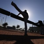 Chicago White Sox pitcher Matt Lindstrom is silhouetted as he stretches during spring training baseball in Phoenix, Thursday, Feb. 21, 2013. (AP Photo/Paul Sancya)