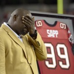 Former Tampa Bay Buccaneers player Warren Sapp wipes his face after being inducted in the Ring of Honor ceremony during halftime in an NFL football game between the Tampa Bay Buccaneers and the Miami Dolphins in Tampa, Fla., Monday, Nov. 11, 2013.(AP Photo/Phelan M. Ebenhack)